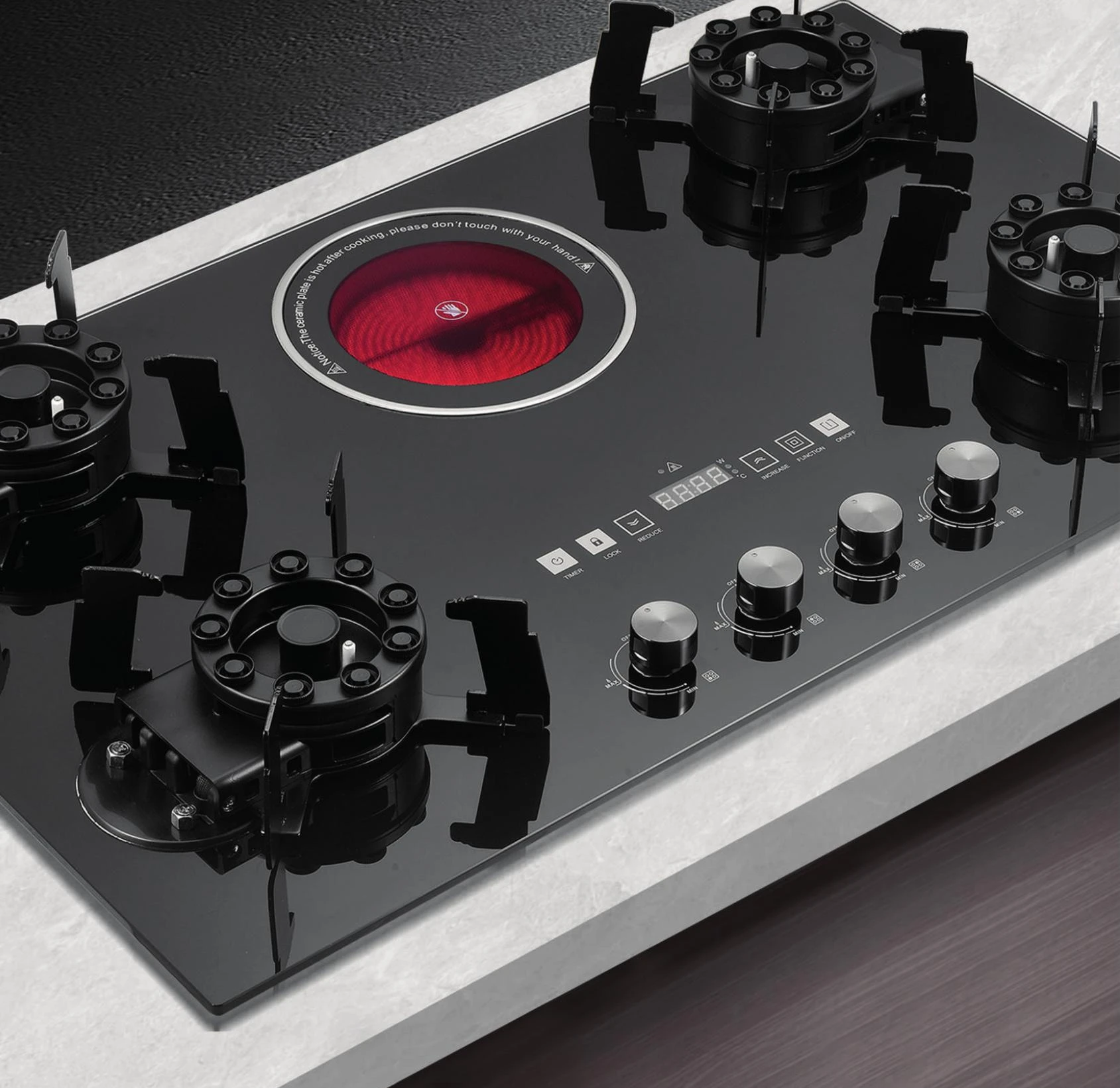Detail of a black glass built-in hob with gas burners and an electric cooking zone